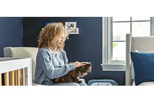 pregnant woman sitting in nursery with cat on lap