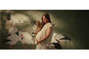 orange cat looking at pregnant woman in nursery
