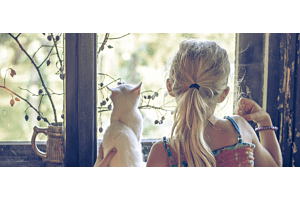 girl and cat looking out a window together