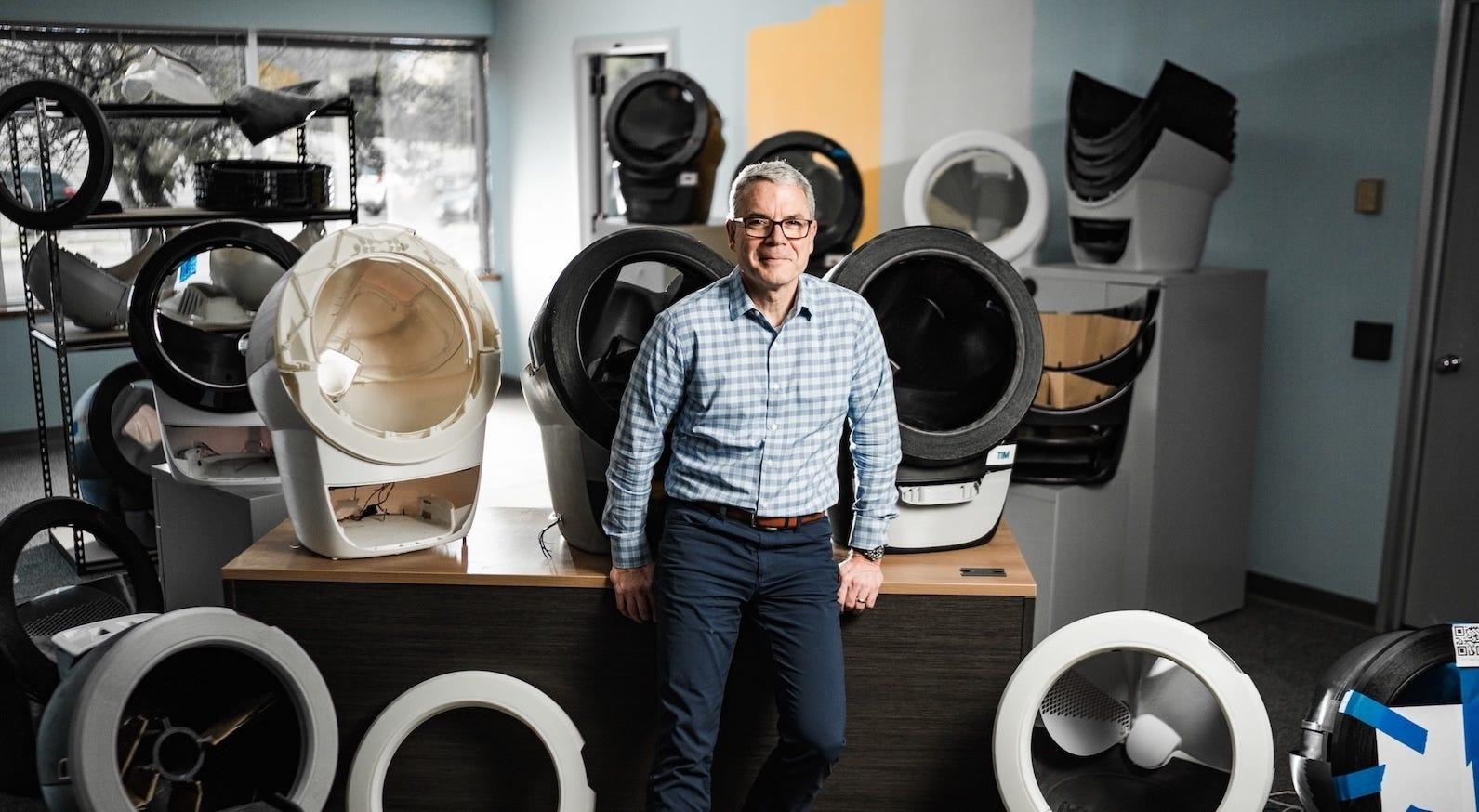 Brad Baxter leaning on desk with multiple Litter-Robot models 
