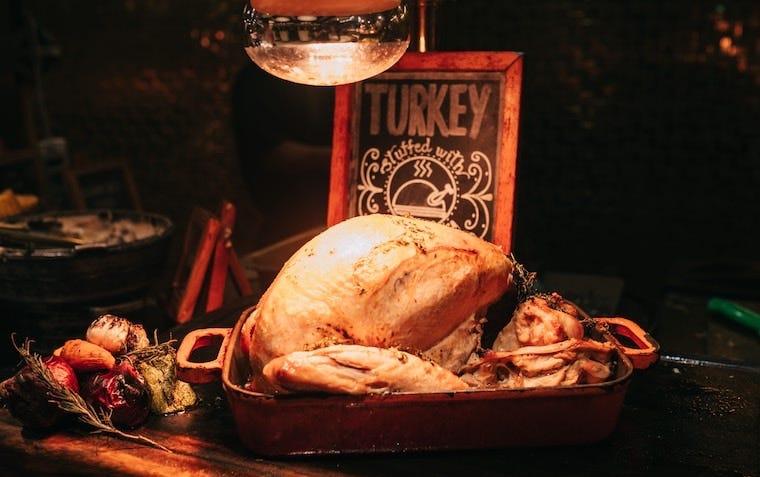 plain turkey in a pan with a turkey sign behind it
