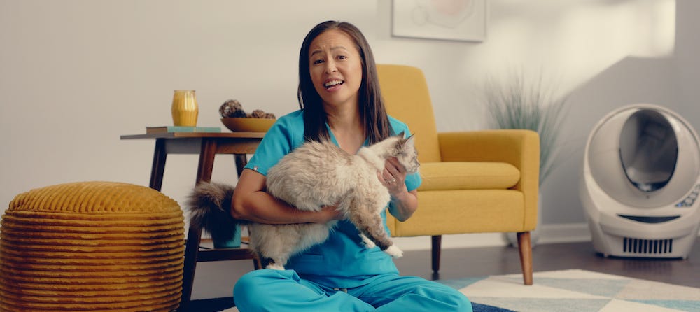 Dr Justine Lee sitting near a Litter-Robot with cat