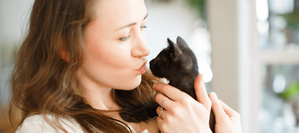 woman cuddling black kitten