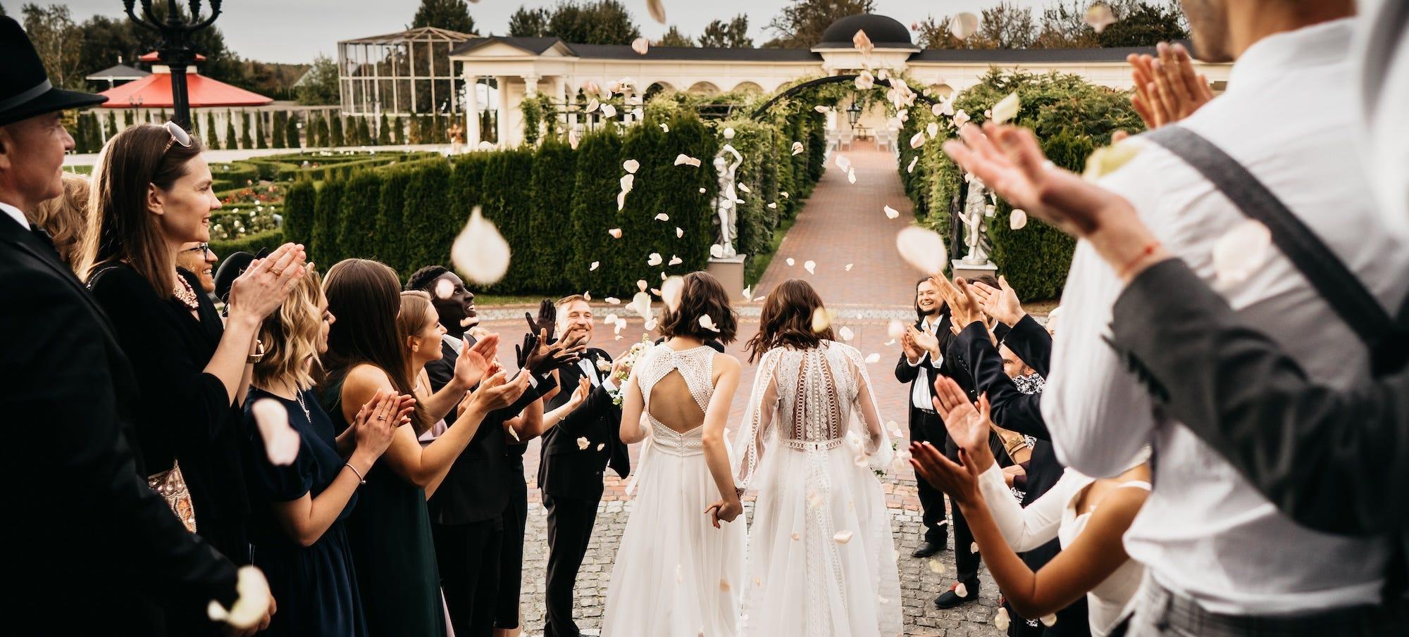 two brides walking between wedding guests