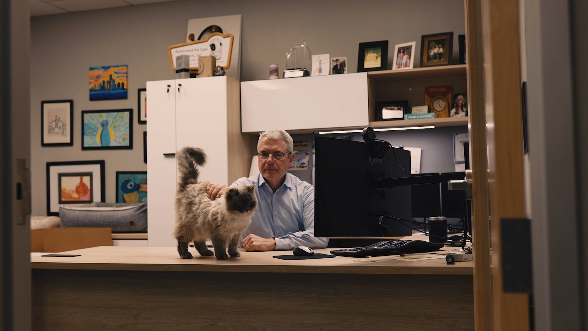 Brad Baxter sitting at his desk with Tank the cat standing on desk