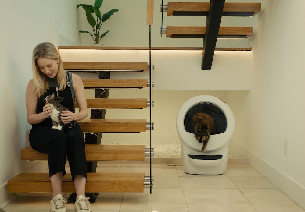 woman petting cat while another cat uses the Litter-Robot 4 automatic litter box
