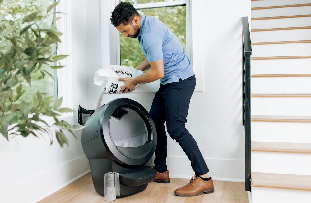 man pouring litter into litterhopper on self-cleaning litter box