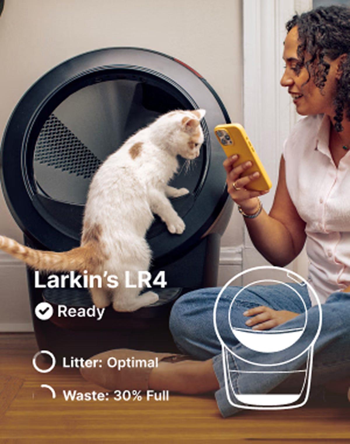 Woman sitting on floor checking the Litter-Robot 4 app on her phone while a white cat climbs into the Litter-Robot 4 with a status overlay showing 'Ready,' 'Litter: Optimal,' and 'Waste: 30% Full'