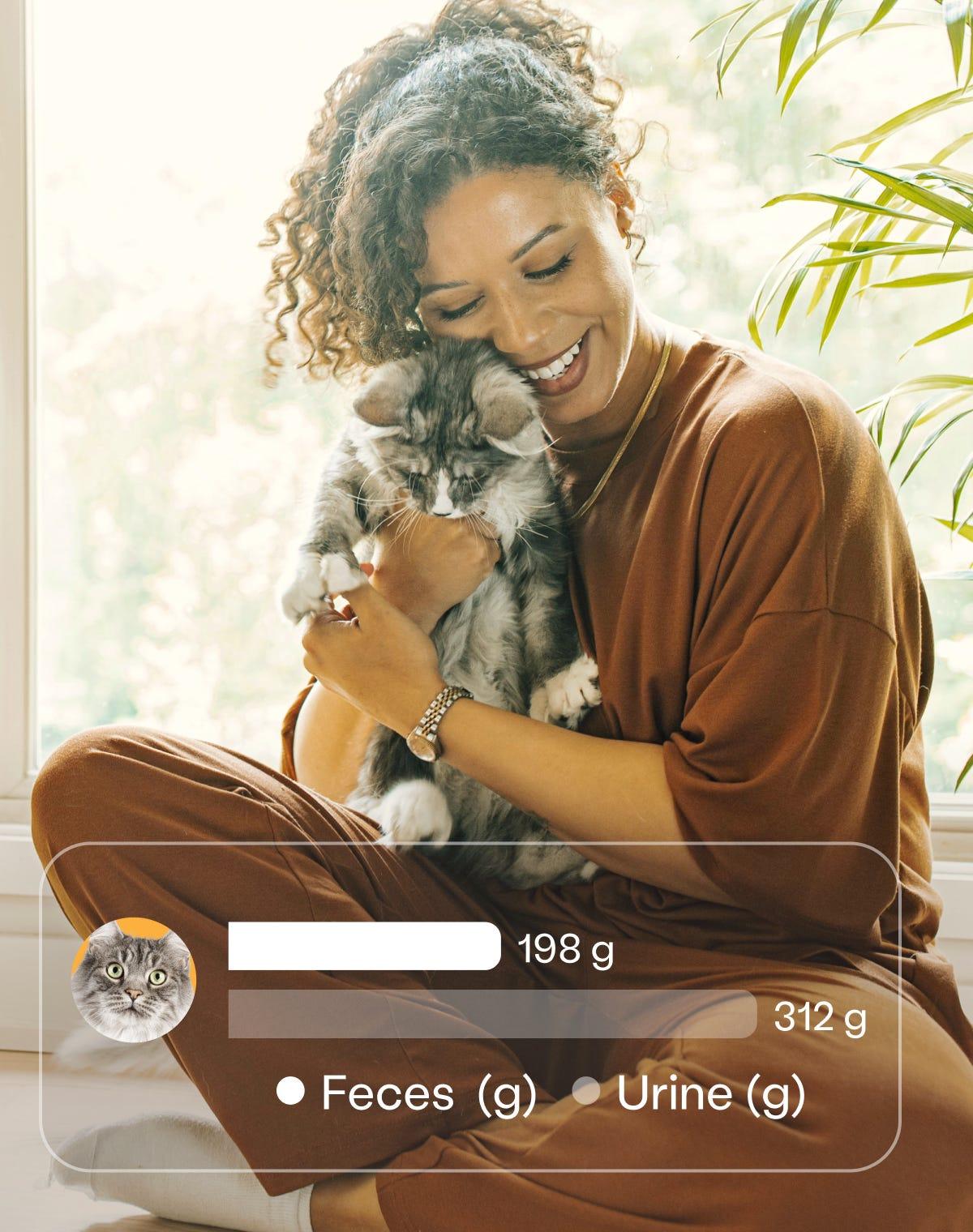 Smiling woman cuddling a fluffy gray cat, with an app overlay displaying waste tracking data: 198g feces and 312g urine