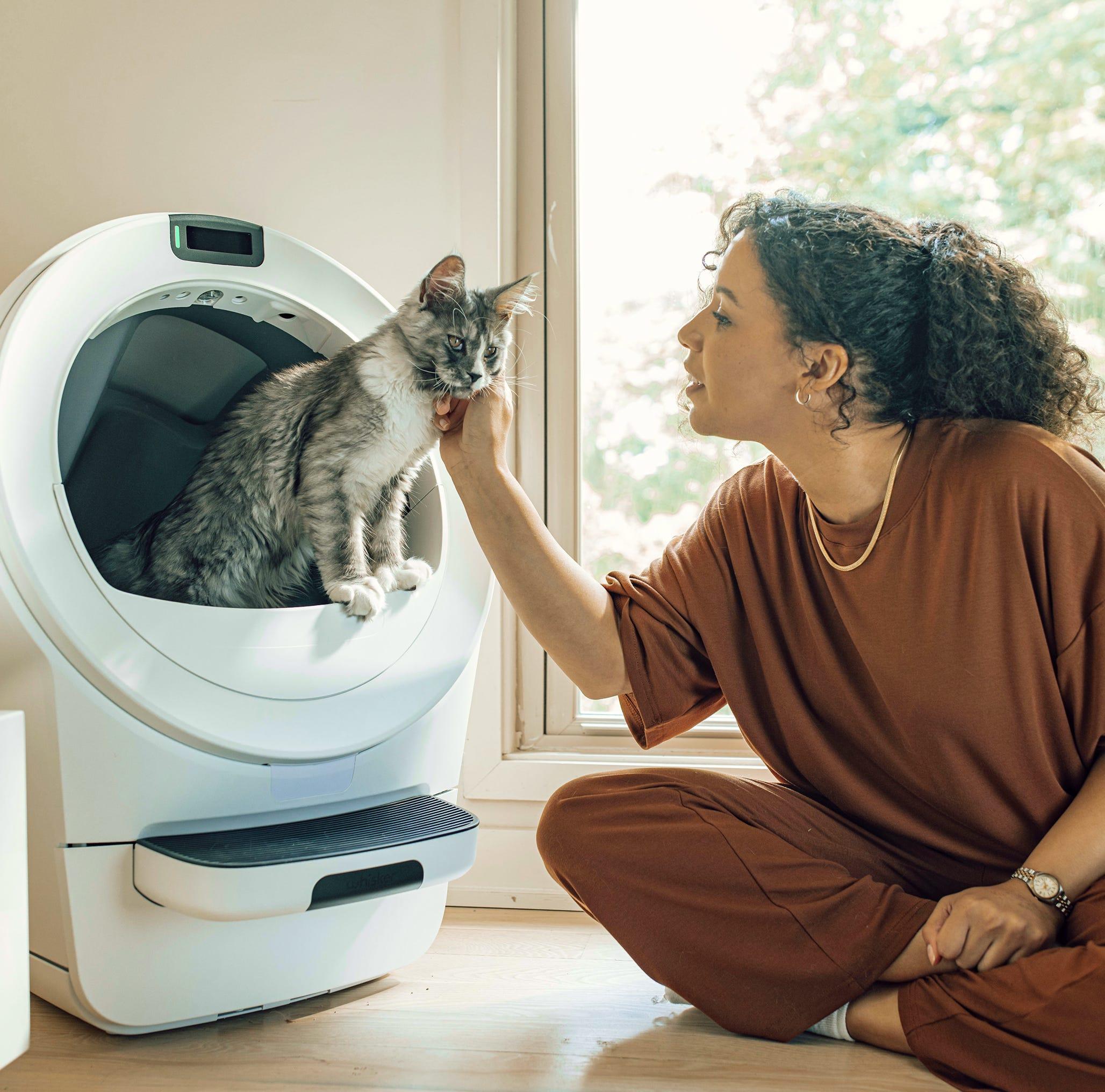 A woman petting a cat inside a Litter-Robot 5.