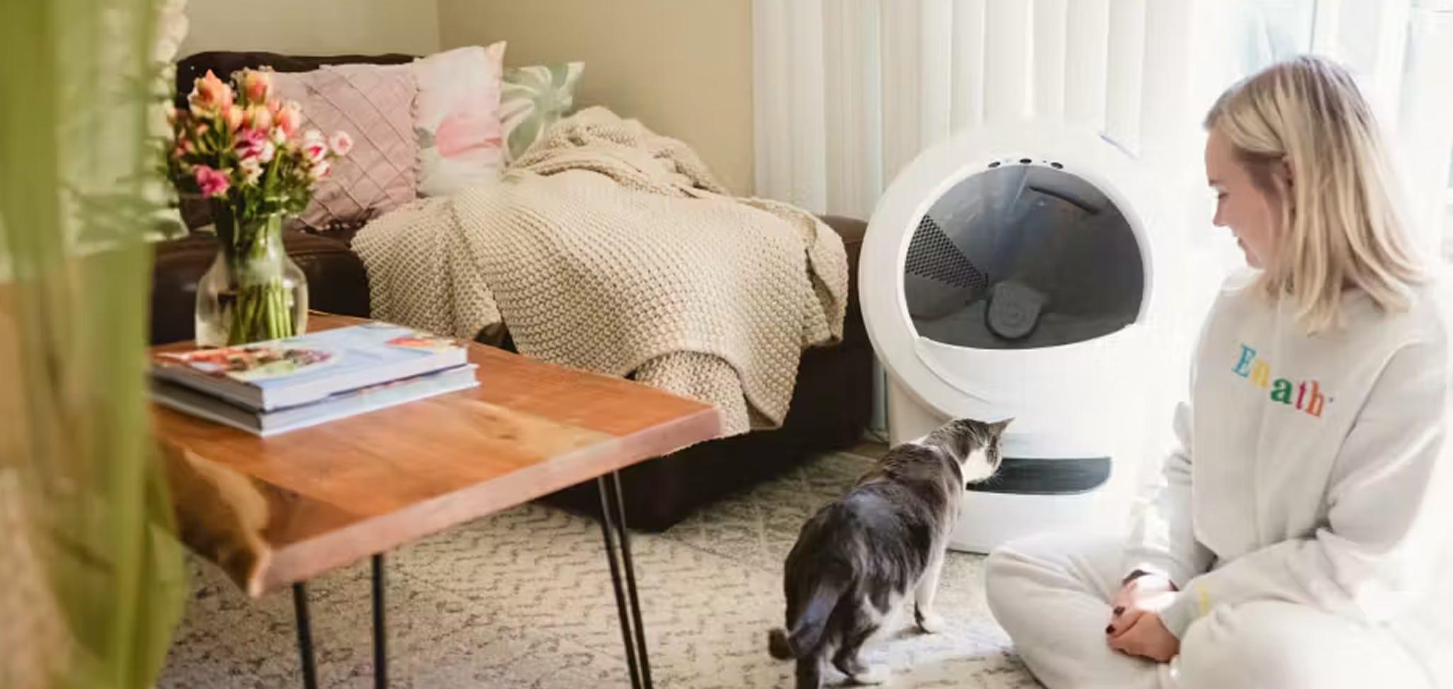 A woman sitting next to a cat with a Litter-Robot 4.