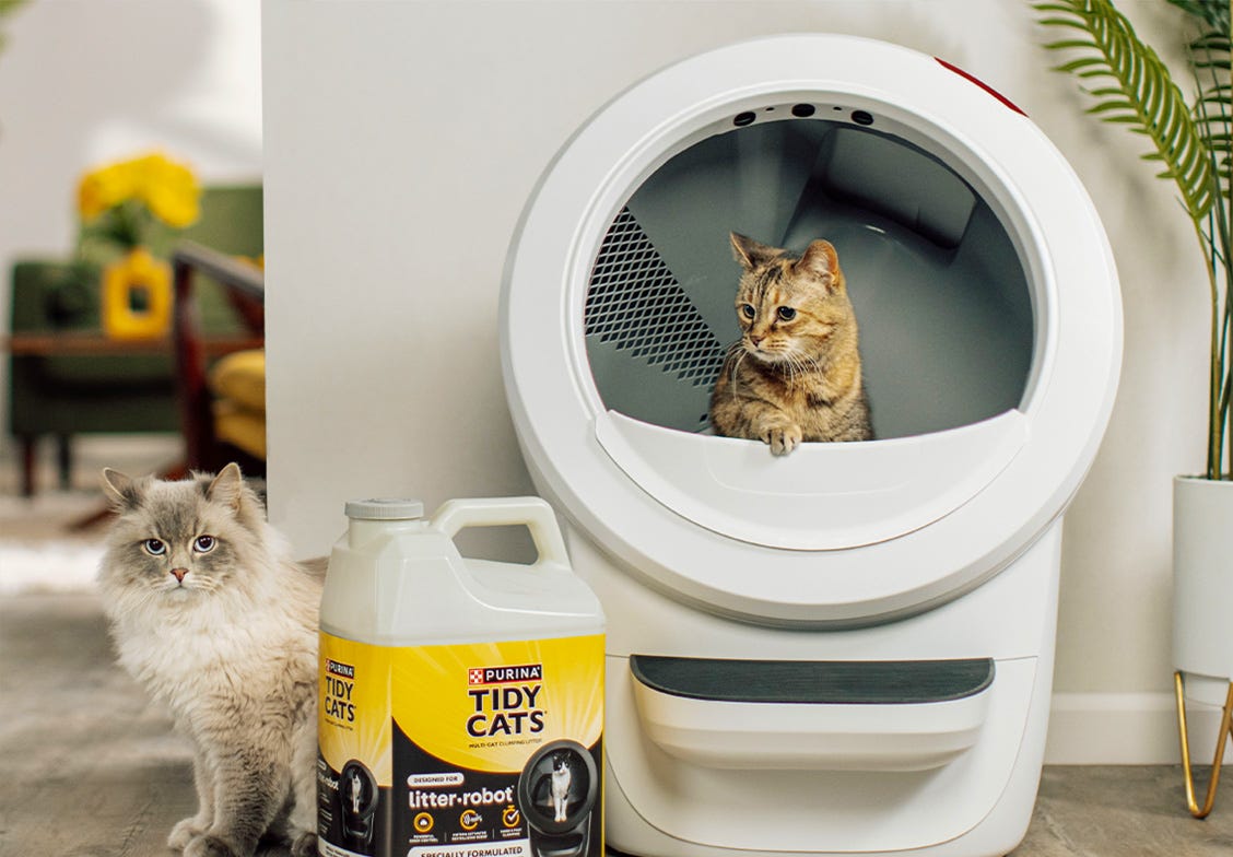 A cat sitting in Litter-Robot 4 with Tidy Cats litter next to it.