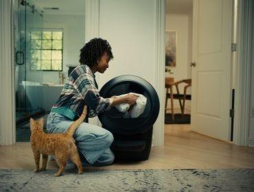 Woman refilling cat litter in Litter-Robot 4 with orange cat