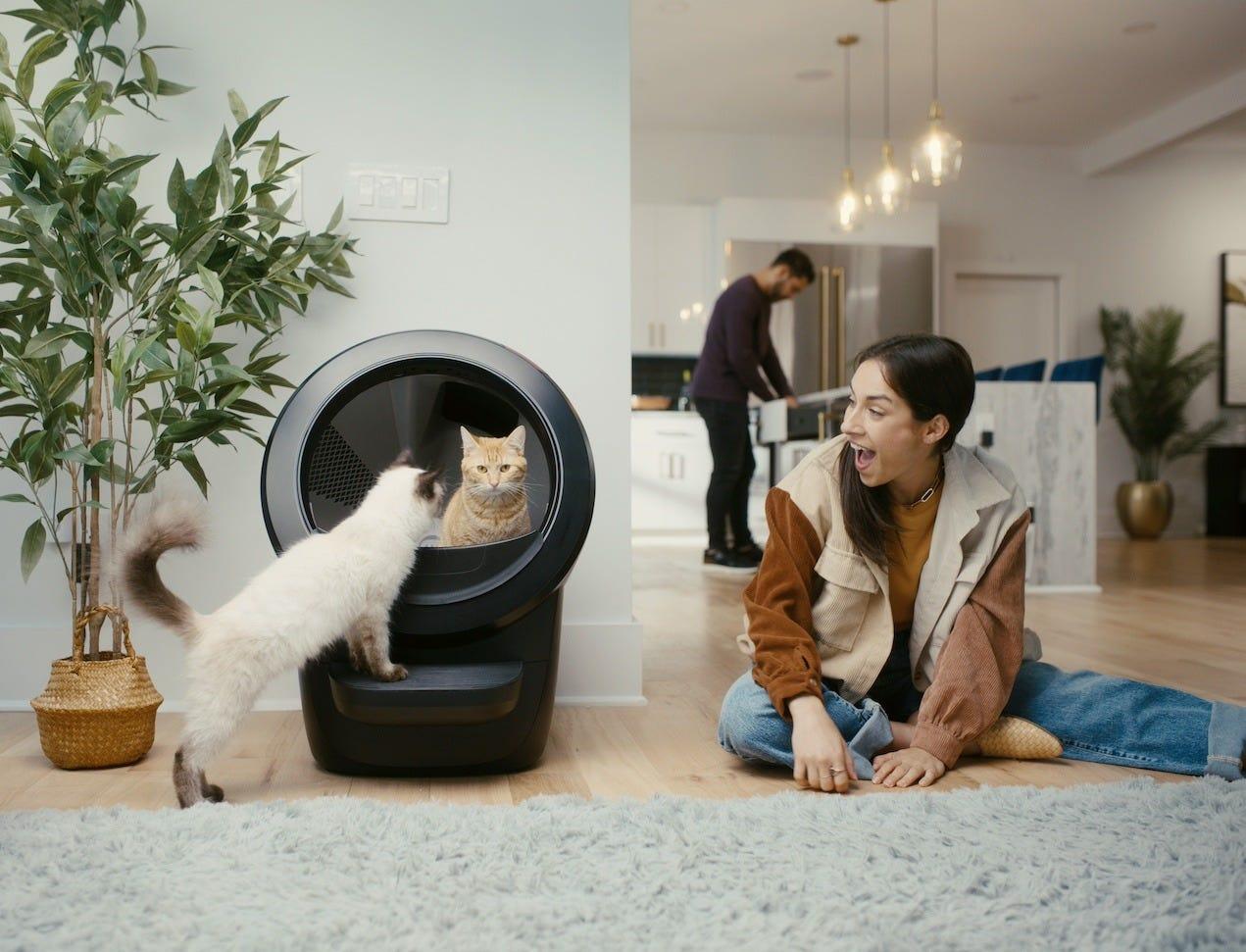 woman sitting with two cats and Litter-Robot 4