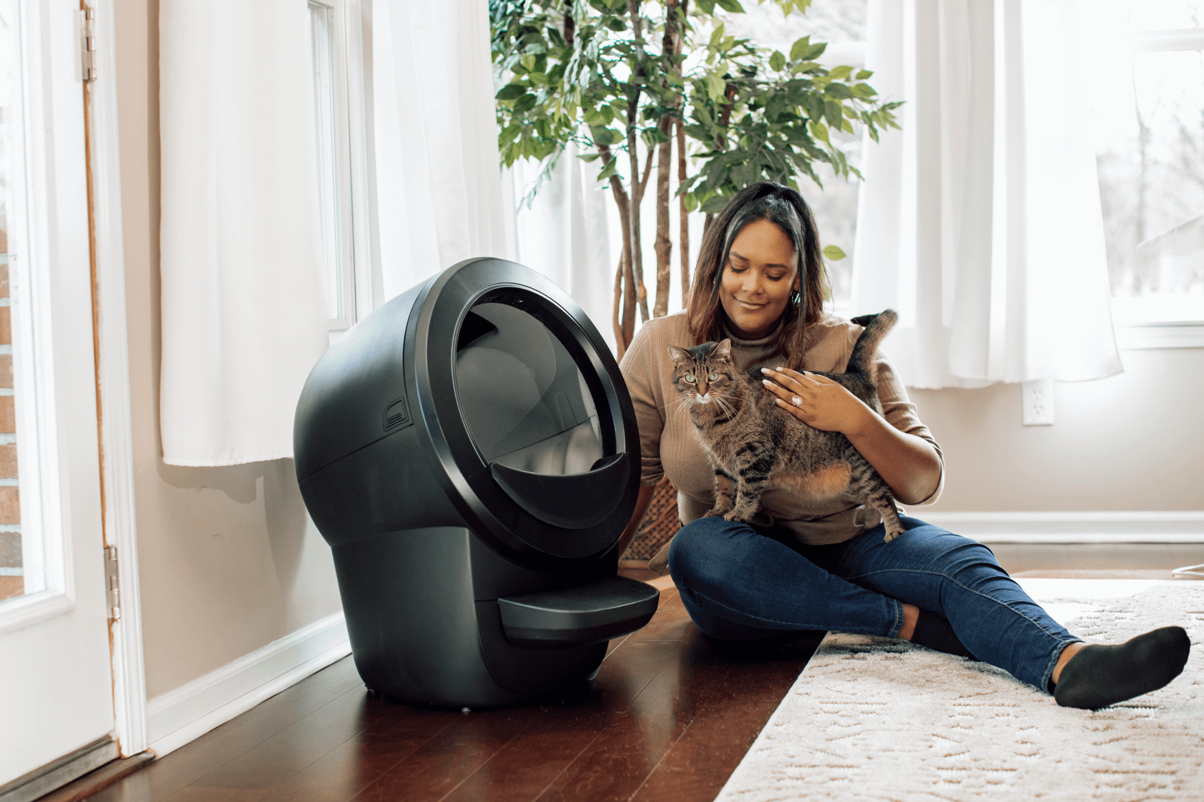 Happy pet owner hugging her cat next to a Litter-Robot 4