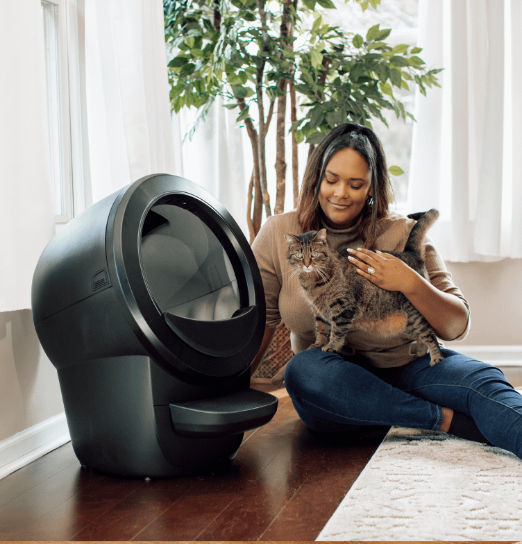 Happy pet owner hugging her cat next to a Litter-Robot 4