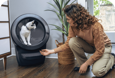 Women kneeling next to cat inside Litter-Robot