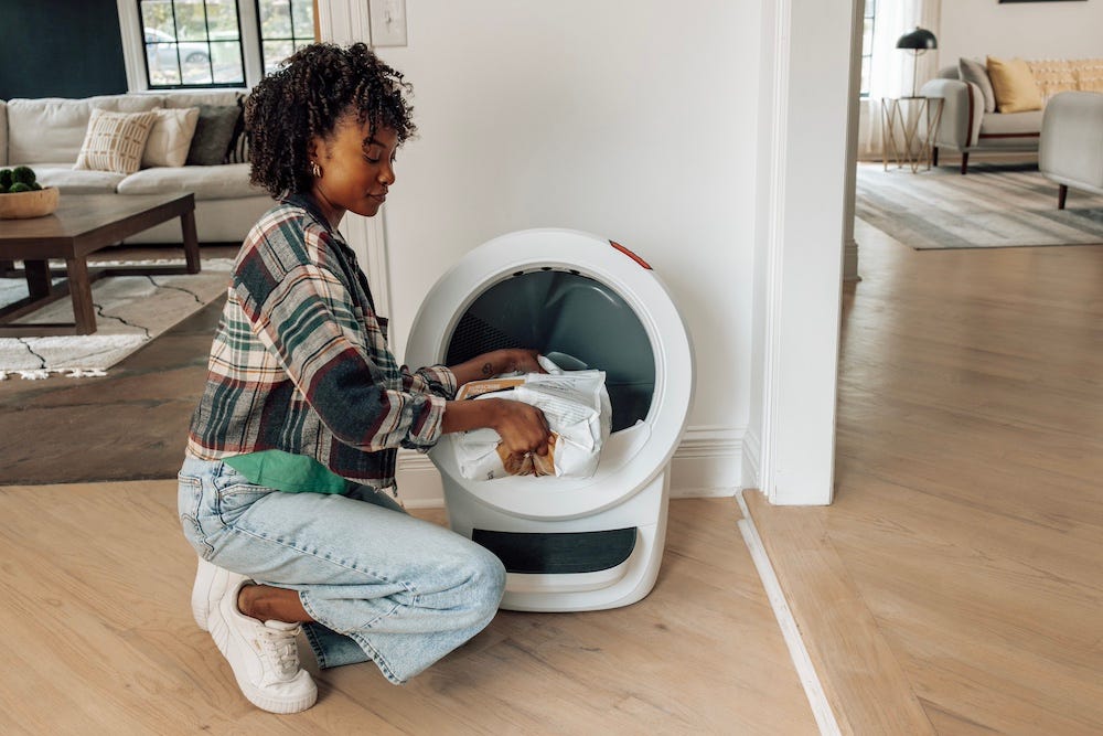 woman adding cat litter to Litter-Robot self cleaning litter box