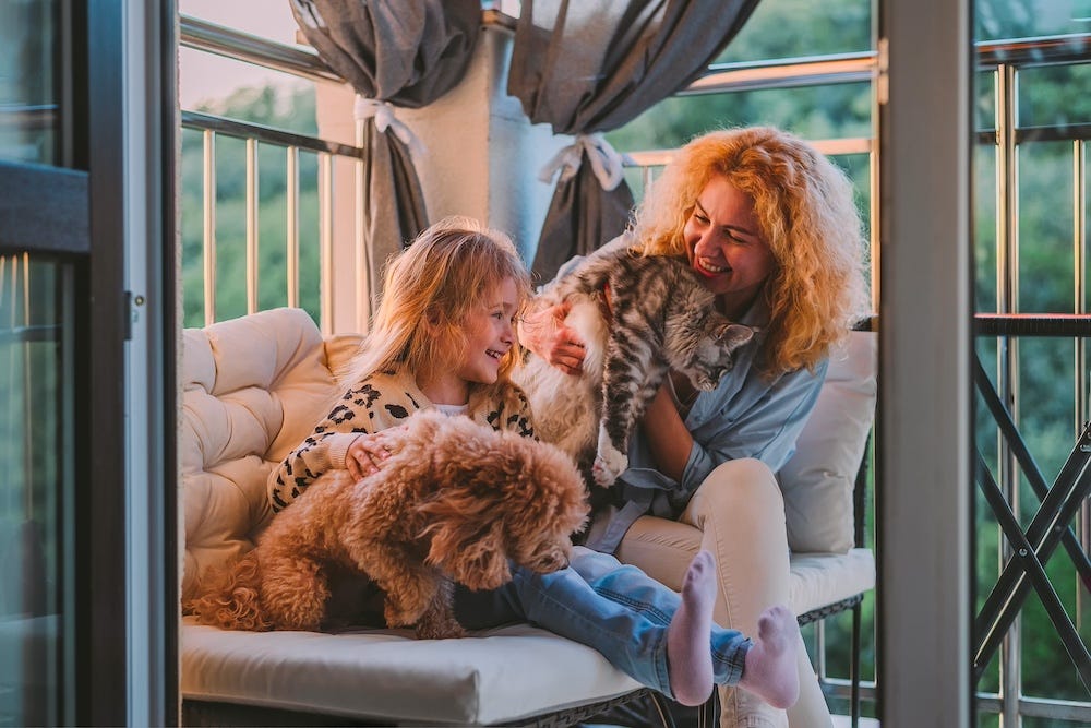 mom and daughter cuddling cat and dog at airbnb
