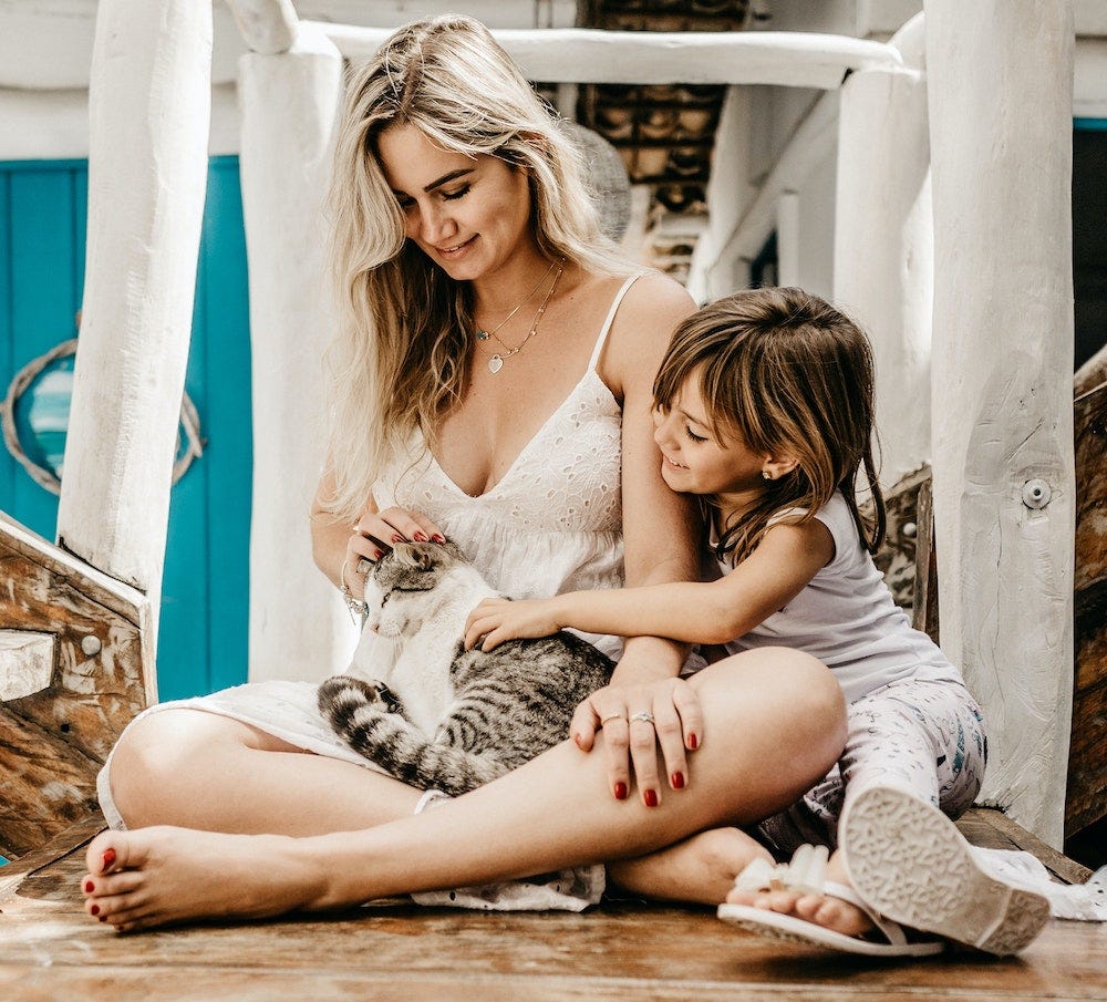 mother and child petting tabby cat
