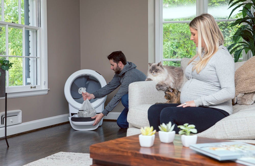 man emptying Litter-Robot near pregnant woman with cat