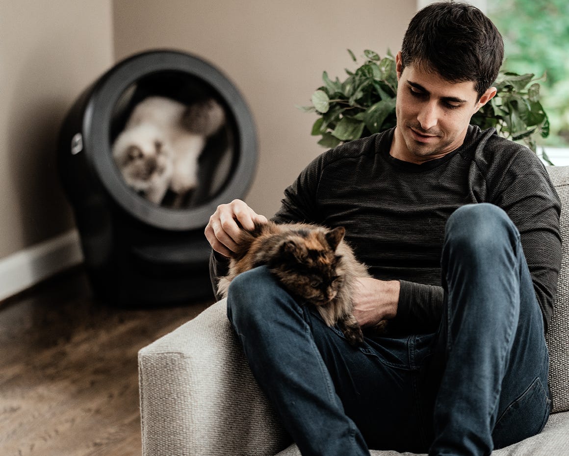 cat using Litter-Robot 4 with man and cat in foreground
