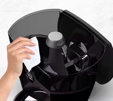 Hand with a cleaning wipe, cleaning a Feeder Robot automatic cat feeder