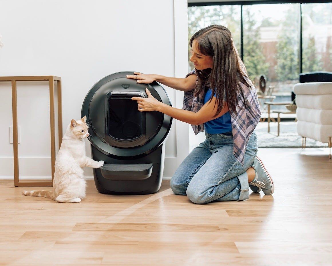 woman attaching Litter-Robot 4 Shield while cat watches